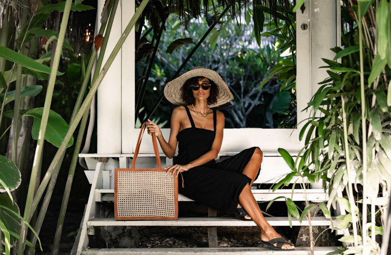 Model wearing straw hat, sunglasses, black maxi dress, and holding Jenn Lee Punta Mita Tote