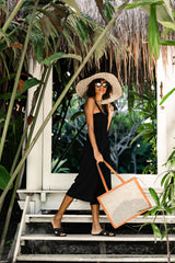 Model wearing straw hat, sunglasses, black maxi dress, and holding Jenn Lee Punta Mita Tote