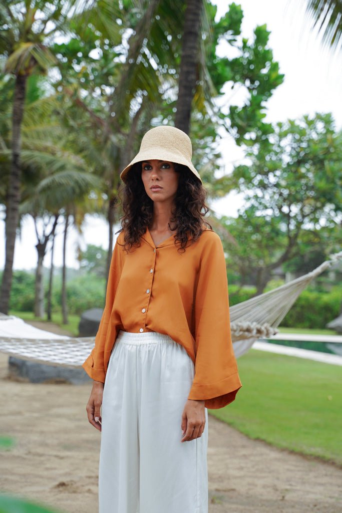 Model wearing straw hat, Jenn Lee Jamu Short SLeeve Shirt, and Jenn Lee Luxe White Pants
