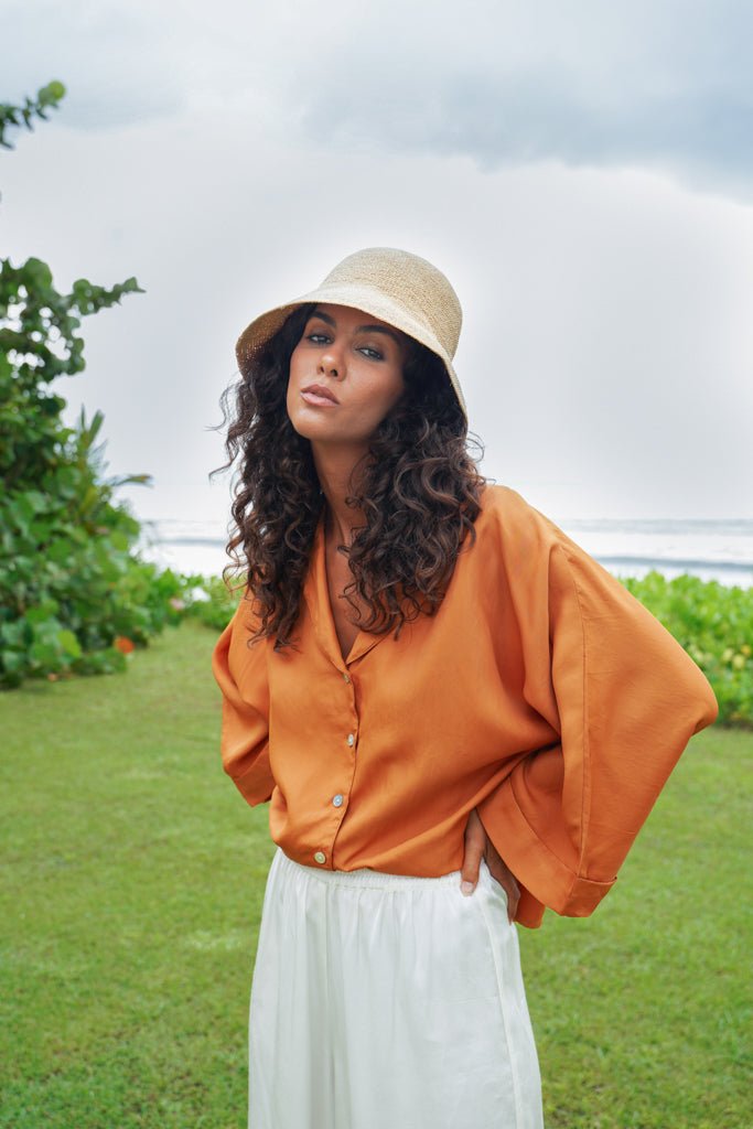 Model wearing straw hat, Jenn Lee Jamu Short SLeeve Shirt, and Jenn Lee Luxe White Pants