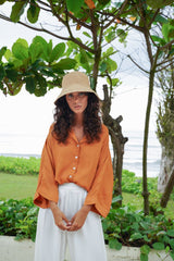 Model wearing straw hat, Jenn Lee Jamu Short SLeeve Shirt, and Jenn Lee Luxe White Pants