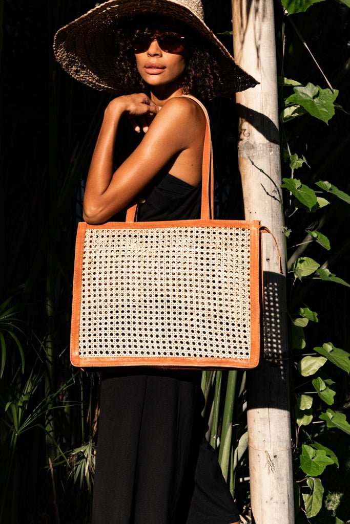 Model wearing straw hat, sunglasses, black maxi dress, and holding Jenn Lee Punta Mita Tote
