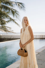 Model wearing cream maxi dress and holding Jenn Lee Seychelles Bag